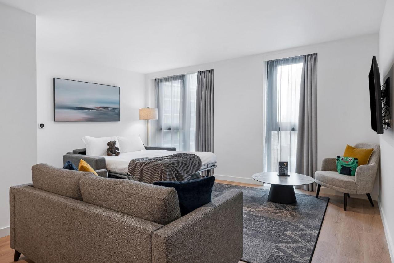 Citysuites 2 Aparthotel Manchester Exteriér fotografie The photo shows a modern living space that incorporates a cozy and inviting atmosphere. It features a light-colored couch with colorful cushions, positioned in front of a coffee table. There's a comfortable armchair nearby, and a throw blanket is dra