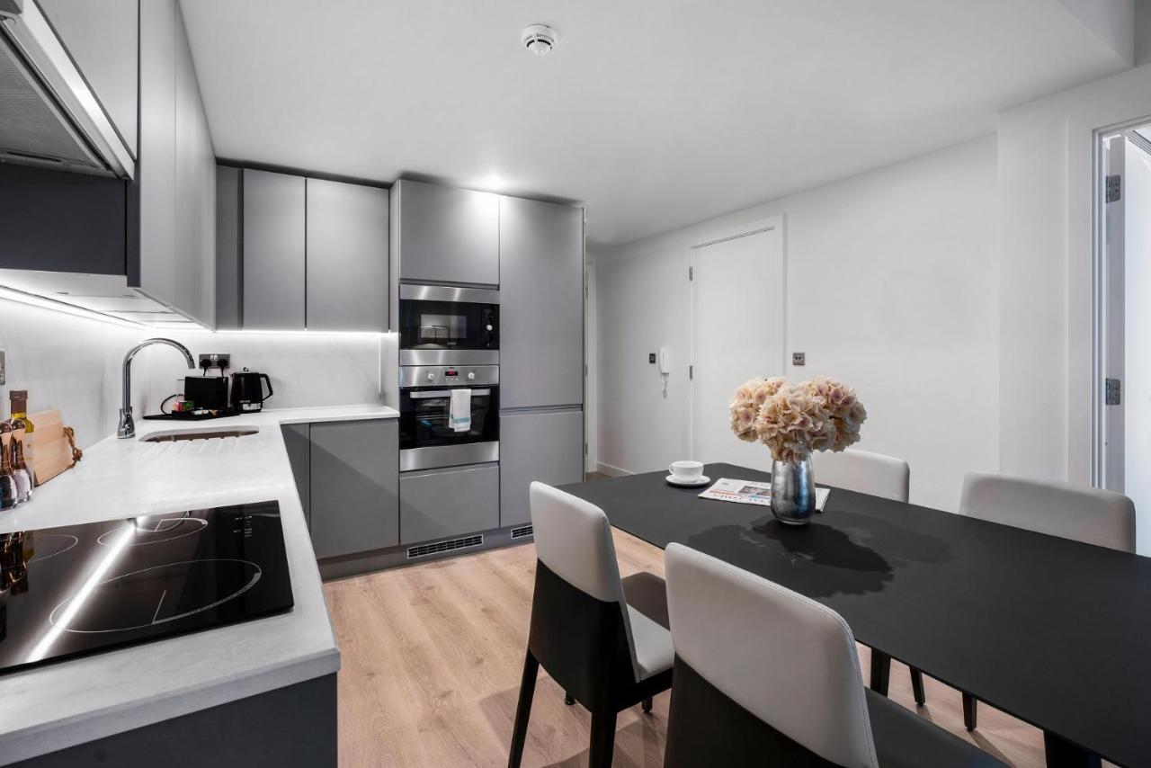 Citysuites 2 Aparthotel Manchester Exteriér fotografie The photo shows a modern kitchen and dining area. The kitchen features sleek gray cabinets, a countertop with an embedded cooktop, and built-in appliances, including an oven and microwave. There’s a small coffee maker on the counter. Adjacent to the 