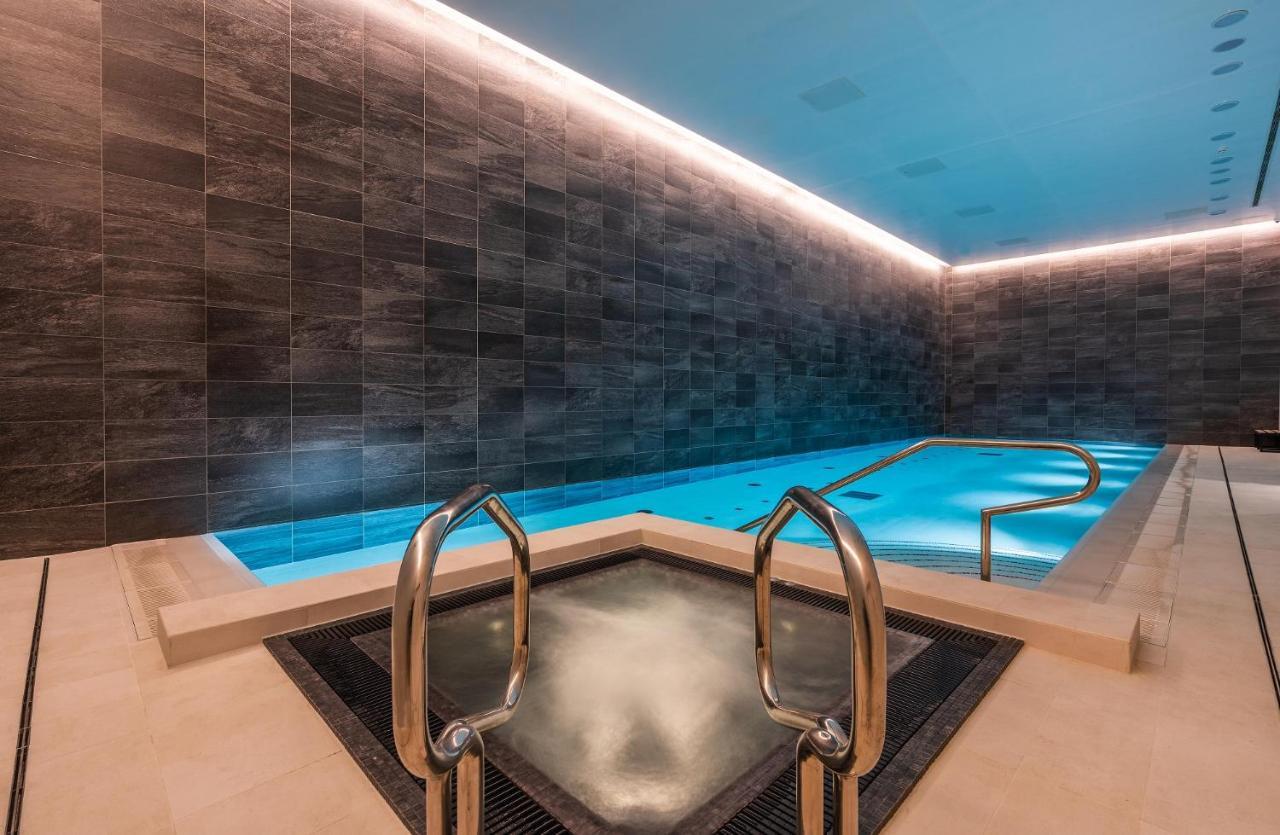 Citysuites 2 Aparthotel Manchester Exteriér fotografie The photo shows a modern indoor swimming pool area. The pool features a sleek, rectangular design with a beautiful blue water that seems illuminated. Surrounding the pool are dark, textured walls, adding to the elegant atmosphere. There are dual meta