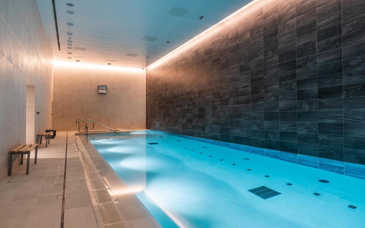 Citysuites 2 Aparthotel Manchester Exteriér fotografie The photo shows an indoor swimming pool area. The pool is illuminated with a soft blue light, creating a calming atmosphere. The walls are designed with dark tiles, and there is a lighter tiled area surrounding the pool. Ambient lighting is installed